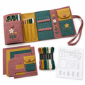 Open felt sewing roll in dusty rose, mustard and teal beside pre-cut pieces, floss and pattern sheet, on white
